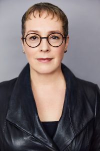 Headshot of Julia Angwin, a white woman wearing black leather jacket and glasses with dark-colored rims.