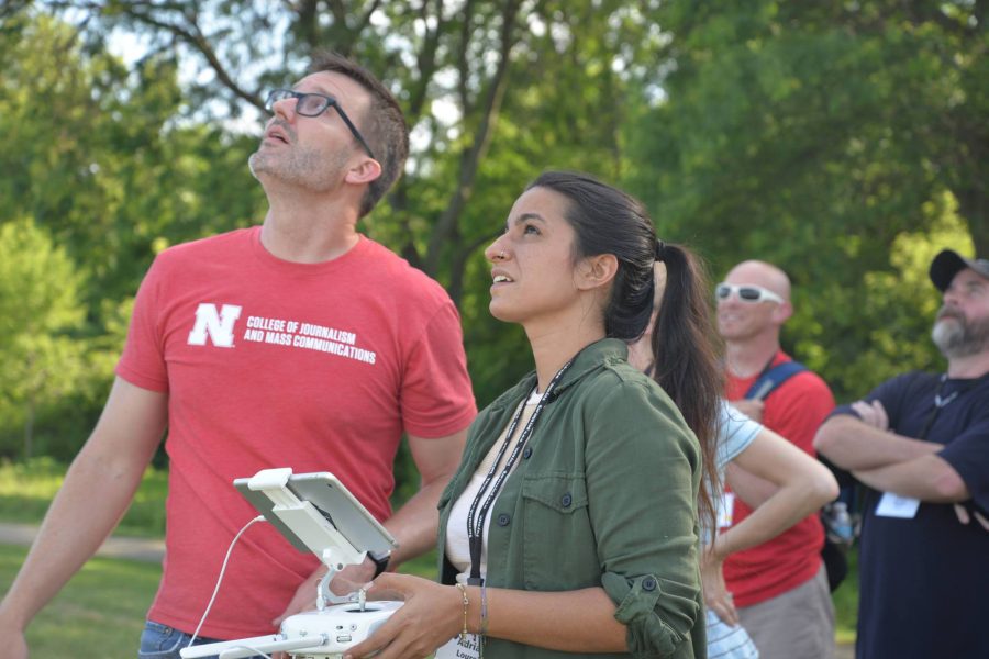 a man and woman look up to the sky as they operate a drone with controllers