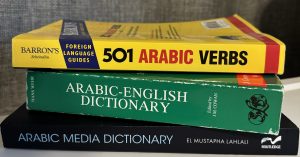 Stack of three books, "501 Arabic Verbs," "Arabic-English Dictionary" and "Arabic Media Dictionary."