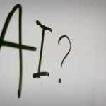 Image shows a whiteboard with "AI?" written on it.