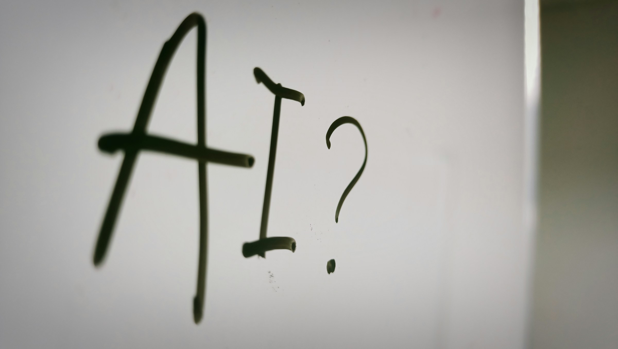 Image shows a whiteboard with "AI?" written on it.